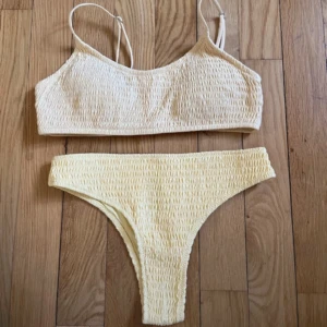 Ljusgul bikini - Ljusgul bikini, överdelen är använd men inte underdelen (remsan sitter kvar), en liten färgskillnad på de, skulle inte säga att man ser de så tydligt. Överdelen är i strl 38 och underdelen i strl 34