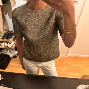 Guldig  topp från by malene birger - Säljer en snygg guldig topp med glittrigt mönster från by malene birger. Passar perfekt för lite festligare tillfällen 🥰