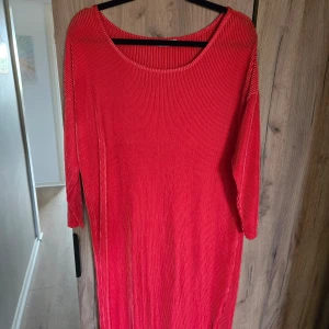 Röd ribbad långklänning - Säljer en röd långklänning med rund halsringning och långa ärmar. Klänningen har en ribbad struktur som ger en snygg och modern känsla. Perfekt för dig som gillar enkel men stilren design.