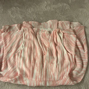 Vit och rosa långklänning från Xoul Edition - Säljer en kort klänning  från Xoul Edition i storlek 34. Klänningen är vit med rosa ränder, har v-ringning och är armlös och har en dragkedja i ryggen. Jag säljer då den inte kommer till användning och den passade inte mig priset kan diskuteras💗