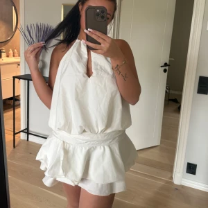 Vit halterneck klänning med volang - Supersöt vit klänning med volangkjol. Klänningen har öppen rygg och knyt i nacken. Supersnygg om rätt person klär den!!💜