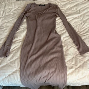 Ljusbrun ribbad långärmad klänning från 157 - Säljer en ljusbrun ribbad klänning från 157 i storlek XS. Klänningen har lång ärm, v-ringning och är figurnära med stretchigt material. Perfekt för dig som gillar enkel och stilren design.