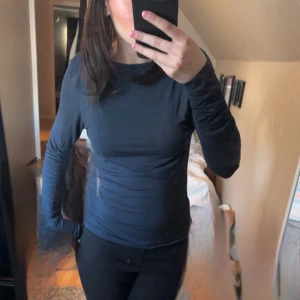 Mörkblå långärmad topp med öppen rygg - Säljer en mörkblå långärmad topp med tight passform och snygg öppen rygg. Perfekt för dig som vill ha en enkel men ändå stilren look. Toppen är i ett mjukt och stretchigt material.
