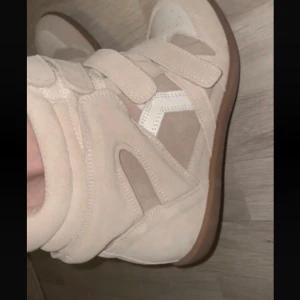 Beige höga isabel marant liknande - Säljer ett par beige höga sneakers med flera breda kardborreband och detaljer i mocka och syntet. Skorna har en rund tå, platt sula och vit detalj på sidan. Perfekta för dig som gillar streetstyle och vill sticka ut. Isabel marant liknande!💕💕