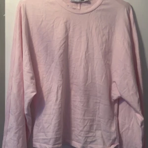 Ljusrosa långärmad tröja - Säljer en ljusrosa långärmad tröja med rund halsringning. Tröjan har en rak passform och har vida ärmar. Den har aldrig använts, endast testad.  På bilden är en precis likadan modell fast i annan färg.
