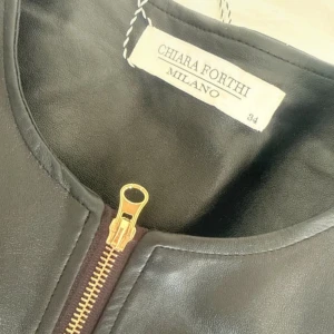 Skinnjacka i str 34 - Snygg svart skinnjacka från Chiara Forthi med guldfärgade dragkedjor framtill och vid fickorna. Jackan har rund halsringning och quiltade detaljer på sidorna och ärmarna. Perfekt för dig som vill ha en stilren och trendig look.