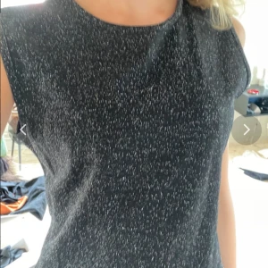 Svart glittrig ärmlös blus från Monki - Säljer en svart ärmlös blus från HENNES med glittrigt mönster. Blusen har rund halsringning och en rak, enkel passform. Perfekt för dig som vill ha något stilrent men ändå med lite extra glitter.