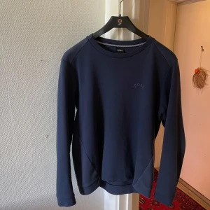 Mörkblå sweatshirt från Hugo Boss, Storlek: S - Säljer en stilren mörkblå sweatshirt från Hugo Boss med diskret logga på bröstet. Tröjan har rund halsringning och långa ärmar. Perfekt för en avslappnad och snygg look.