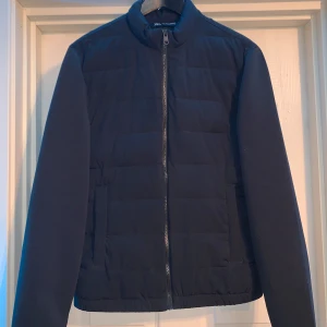 Svart quiltad jacka från Zara - Säljer en svart quiltad jacka från Zara med dragkedja framtill och ståkrage. Jackan har lång ärm och två fickor på sidorna. Perfekt för kyligare dagar och enkel att matcha med olika outfits.