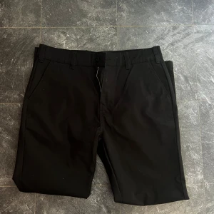 Svarta kostymbyxor från 157 - Säljer ett par svarta kostymbyxor från 157 i storlek L. Byxorna har normal passform, raka ben