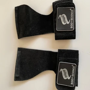 Svarta tränings Straps från Body Science - Svarta tränings Straps  från Body Science med bred kardborrestängning och logotyp på ovansidan. Perfekta för gym och styrketräning, ger bra grepp och skydd för händerna under tunga lyft.