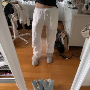 Vita linnebyxor från Chelsea Girls - Säljer ett par vita linnebyxor från Chelsea Girls med resår och snörning i midjan. Byxorna har en avslappnad passform och raka ben, perfekta för varma dagar. Luftigt material som känns skönt mot huden.