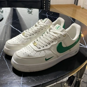 Nike Air Force 1 med gröna detaljer - Säljer ett par fräscha Nike Air Force 1 med vit bas och gröna detaljer på swoosh, häl och tunga. Klassisk siluett med perforerad tå, platt sula och snörning. Perfekta för dig som vill sticka ut lite extra med en clean look. Priset är inte hugget i sten (original pris 3000)