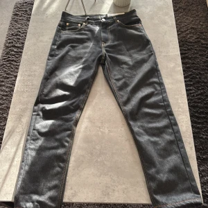 Evisu jeans med vit grafik på baksidan - Säljer ett par gråa jeans från Evisu med unik vit grafik på baksidan av benen. Klassisk femficksmodell med kontrastsömmar och läderpatch i midjan. Perfekta för dig som vill sticka ut med en streetwear-look.