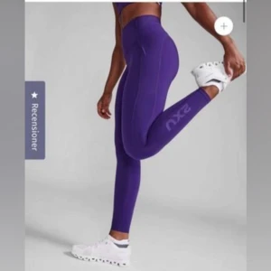 Lila träningstights från 2XU - Säljer ett par lila träningstights från 2XU med hög midja och tight passform. Perfekta för gymmet eller löpning. Snygg och sportig design. Ordinarie pris är 1299kr. Heter Form Stash Hi-rise Compression Tights på hemsidan💗