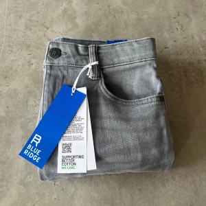 Gråa jeans från Blue Ridge - Säljer ett par grå jeans från Blue Ridge med klassisk femficksdesign och knappgylf. Jeansen har en slim passform. Perfekta för en stilren vardagslook. Slim/skinny fit. Storlek 158. 