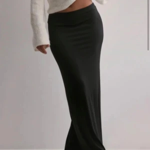 Svart maxikjol med låg midja från Nelly - Säljer en svart maxikjol med låg midja från Nelly. Kjolen har en ganska tight passform och den är i XXS. Helt oanvänd med prislappen kvar 🥰