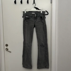 Grå bootcut jeans från Gina Tricot - Snygga grå bootcut jeans från Gina Tricot. De har en klassisk femficksdesign och knappar fram. Perfekta för en avslappnad stil med en touch av retro.