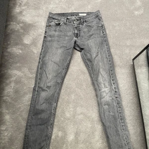 Grå jeansbyxor - Snygga grå jeansbyxor med en klassisk femficksdesign. De har en dragkedja och knapp framtill. Tillverkade i Italien, dessa byxor har en stilren look som passar perfekt för olika tillfällen.