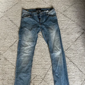 Blå jeans från Smog - Säljer ett par snygga blå jeans från Smog. De har en klassisk femficksdesign och en knappgylf. Perfekta för en avslappnad stil. Storlek 29/32.  