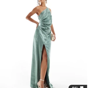 Eucalyptus-färgad one-shoulder balklänning - Superfin glansig draperad klänning i grön/blå satin med slits 🤍 Helt nyköpt, aldrig använd med lapp kvar perfekt till balen! Sitter jättefint och har en sån fin och unik färg, skriv för mer bilder eller frågor :)