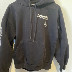 hoodie Carhartt - Säljer en svart hoodie från Carhartt med tryck på både fram- och baksida samt ärmarna. 