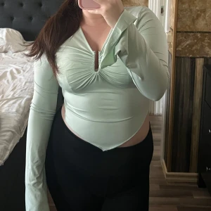 Ljusgrön långärmad topp - Snygg ljusgrön topp med långa ärmar. Toppen har en åtsittande passform och en unik design med en liten volangdetalj vid ärmsluten. Perfekt för sommaren!! Aldrig använd 