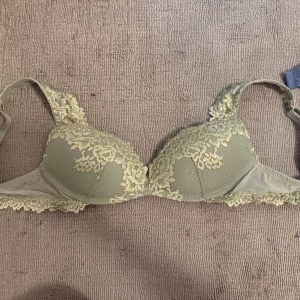 Grön spets-bh - Elegant grön bh med vacker spetsdetaljering från Intimissimi o storlek 75b. Den har justerbara axelband och en mjuk kupa för extra komfort och push upp . Perfekt för att känna sig både bekväm och stilfull. Endast använd 1 gång säljes då den var för liten, nypris 500 kr mitt pris 370 kr