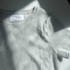 Grå kortärmad tröja från Zara - Säljer en stilren grå kortärmad tröja från Zara. Perfekt för en avslappnad look. Tröjan har en rund halsringning och är gjord i ett mjukt material. Superfint skick!