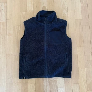 Mörkblå fleeceväst med dragkedja storlek S - Säljer min brorsas mörkblå fleeceväst med dragkedja och hög krage. Västen har en praktisk bröstficka och två sidofickor med dragkedjor. Passade han när han var runt 165-170.