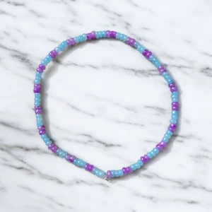 Färgglatt pärlarmband - Säljer ett färgglatt armband med pärlor i blått och lila. Perfekt för att ge en pop av färg till din outfit. Armbandet är elastiskt och passar de flesta handleder.