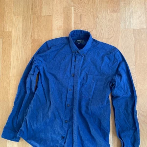 Blå långärmad skjorta från Vailent - Snygg blå långärmad skjorta från Vailent med klassisk krage och knappar framtill. Perfekt för en stilren look. Skjortan har en bröstficka som ger en extra touch. Passar bra till både jeans och chinos. Den är i nyskick och knappt använd nypris 500