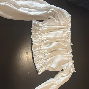 Vit offshoulder blus - Säljer en söt vit offshoulder blus med långa ärmar och elastiska detaljer vid hals och midja. Perfekt för en somrig look! 💫
