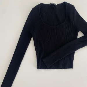 Svart ribbad topp från Missguided - Snygg svart ribbad topp från Missguided med långärmad design och en stilren, figurnära passform. Perfekt för att skapa en chic look. Storlek EU 38.