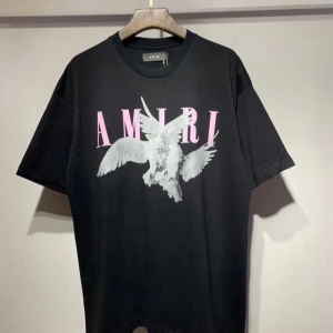 Svart t-shirt från Amiri med tryck - Snygg svart t-shirt från Amiri med ett coolt tryck av en vit fågel och rosa text på framsidan. 