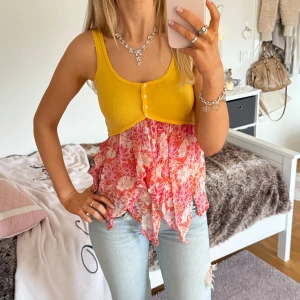 Gul och rosa blommig linnetopp - Säljer en färgglad linnetopp i gult och rosa med blommigt mönster. Toppen har en unik design med knappar framtill och en volangdetalj i nederkant. Perfekt för sommarens varma dagar! ⊹ jag är 173cm & stl S/36/28 för referens ⊹ läs POLICY (i gillade inlägg) innan köp ⊹ använd gärna ”Köp” ⊹ 