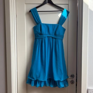 Blå klänning med volangdetaljer - Så gullig blå klänning med breda axelband och volangdetaljer i nederkant. Perfekt nu inför sommaren!! 