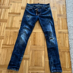 Blå jeans från Dsquared2 - Snygga blå jeans från Dsquared2 med slitna detaljer och en cool, distressed look. De har en klassisk femficksdesign och en läderpatch med logotypen på baksidan. Perfekta för en avslappnad stil.