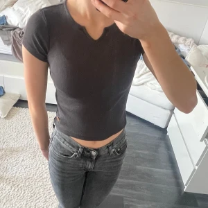 Grå ribbad topp med v-ringning - Säljer grå ribbad topp med v-ringning. Toppen har korta ärmar och en liten logga på nederkanten. Den är i storlek 134/140 men fungerar på mig som har xs💕