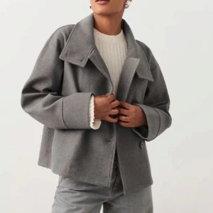 Grå kappa från Gina  - Kort grå kappa från Gina tricot med knäppning framtill. Väldigt fint skick, knappt använd. Strl L men passar mig som vanligtvis har M i jackor! 