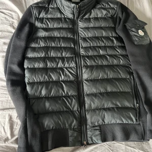 Svart cardigan jacka från Moncler säljs och bytes mot rätt - Snygg svart cardigan jacka från Moncler med dragkedja framtill. Jackan har långa ärmar och en praktisk ficka med knapp på ärmen. Perfekt för kyligare dagar. Scan funkar hör av er om ni vill ha bild bevis! Kan byta om det är nått bra helst under armour jacka