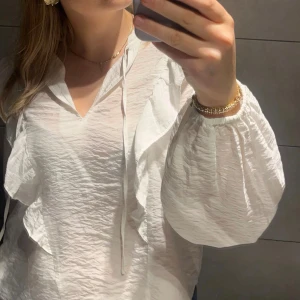 Vit volangblus  - Jättefin blus! Har en prick på ryggen som man ser på sista bilden. Pricken går inte bort men är inte stor.