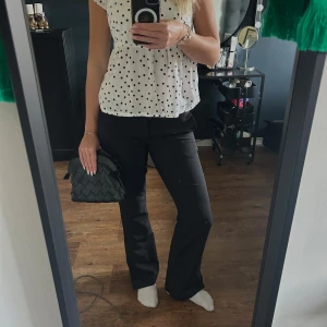 Svarta kostymbyxor - Snygga svarta kostymbyxor med låg midja och bootcut passform. Perfekta för en stilren look. Byxorna har en klassisk design med diskreta fickor.