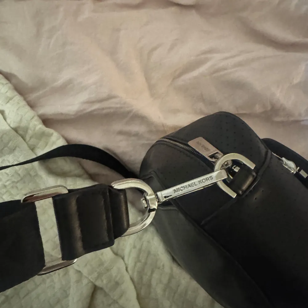 Snygg svart axelväska från Michael Kors med justerbar axelrem och flera praktiska fack med dragkedja. Perfekt för att hålla ordning på dina saker med stil. Väskan har en stilren design med subtila detaljer. Cross body bag, perfect for daily use or traveling (has many pockets) the condition is amazing. Was purchased in Miami. Open to negotiation. . Laukut & Käsilaukut.