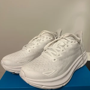 Hoka Clifton 9 - Vita löparskor från Hoka i modellen Clifton 9, använda 2 gånger, storlek 39 1/3 (24,5 cm), jätte sköna att springa i tack vare den tjocka sulan som ger mycket dämpning