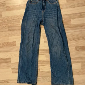 Blå jeansbyxor - Säljer ett par klassiska blå jeansbyxor från Denim. De har en rak vid passform och är tillverkade i ett tunnare jeansmaterial. Perfekta för en avslappnad stil. En liten lagning på baken, och trasiga i kanten längst ned. skrynkliga pga förvaring i låda. 
