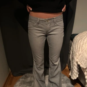 Grå bootcut jeans - Snygga grå bootcut jeans med låg midja. Perfekta för en avslappnad stil. Klassisk femficksdesign och knappgylf.                  Omsydda jeans  Grenmått: 17,5 cm Midjemått: 36 cm Innerbenslängd: 76 cm 