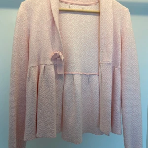 Kofta med rosett - Rosa kofta med mönster som har en rosett. Är super fin och skön. Skriv vid eventuella frågor🩷