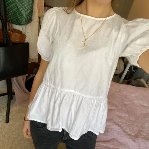 Vit blus från H&M - Säljer denna super söta vita blus från H&M med puffiga korta ärmar och en volangdetalj vid kanten . Blusen har en liten knappöppning i nacken. Är från H&M i storlek 12-13, men passar superbra som xs-s🤗💓