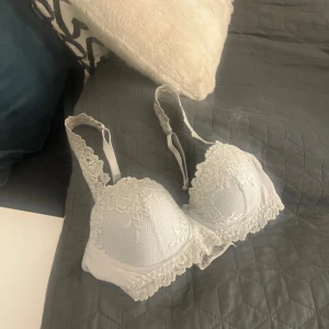 Intimissmi BH 75B - Säljer en elegant vit bh med spetsdetaljer. Den har justerbara axelband och en mjuk kupa för extra komfort. Perfekt för att känna sig både bekväm och stilfull. Använt max fem gånger säljer då den inte kommer till användning.